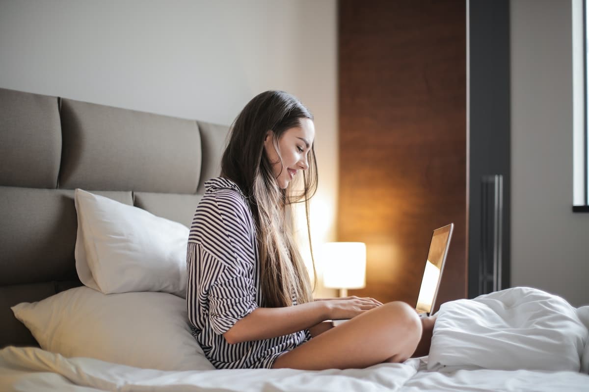 vrouw op bed met laptop